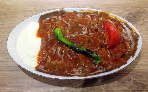 Traditional Kebaptan İskender kebab with thinly sliced döner, tomato sauce, and melted butter over pide bread
